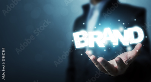 Branding idea concept. Businessman hand holding word BRAND with bokeh background