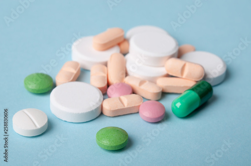 various pills, tablets and capsule of medicine on blue background; medical care and safe drug use concept