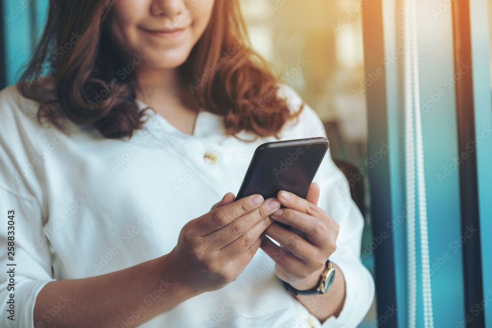 Closeup image of a woman holding , using and looking at smart phone in cafe Closeup image of a woman holding , using and looking at smart phone in cafe