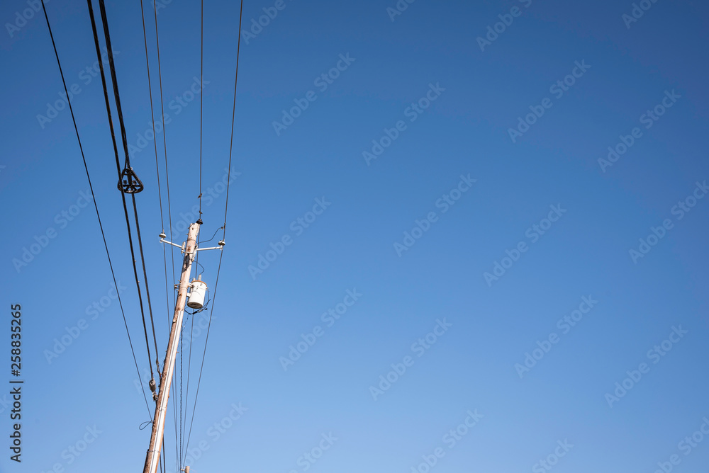 Electric poles with wires and cables set on a bright blue daylight sky. Electric poles with wires and cables set on a bright blue daylight sky.