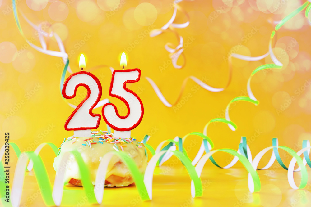 Twenty five years birthday. Cupcake with burning candles in the form of number 25. Bright yellow background with copy space