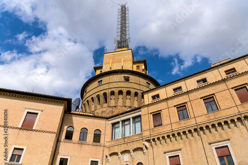 Vatican Radio Tower - A close-up low-angle view of Vatican Radio Building and its big radio masts, against white clouds and blue sky of sunny October morning, in Vatican Gardens. Vatican City, Italy.