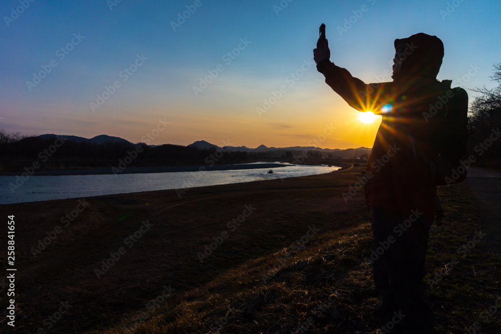 美しい風景写真を撮影する男性　スマートホン　夕日