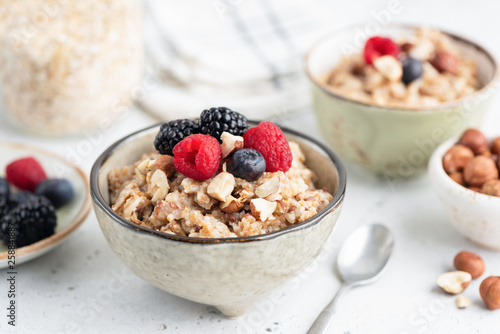 Foto Healthy breakfast cereal porridge with berries and nuts in bowl