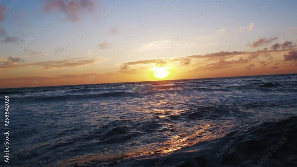 Sea birds floating in waves. Glowing orange sunset drapes beach in purples and pinks blues. Calming, relaxing, California Coast. Sea birds floating in waves. Glowing orange sunset drapes beach in purples and pinks blues. Calming, relaxing, California Coast.
