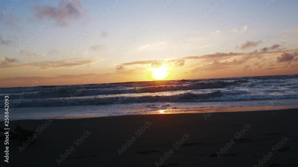 Setting sun reflects on sand. Glowing orange sunset drapes beach in purples and pinks blues. Calming, relaxing, California Coast. Setting sun reflects on sand. Glowing orange sunset drapes beach in purples and pinks blues. Calming, relaxing, California Coast.