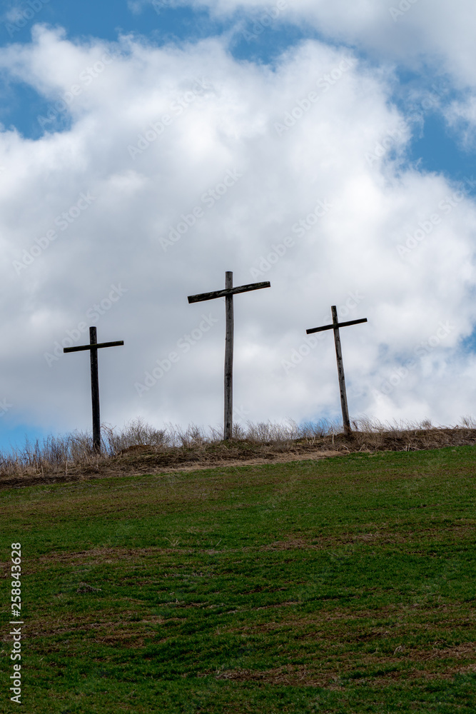 3 Wooden Crosses On hillside With Blue Cloudy skies In Remembrance of Religious Easter holiday 3 Wooden Crosses On hillside With Blue Cloudy skies In Remembrance of Religious Easter holiday