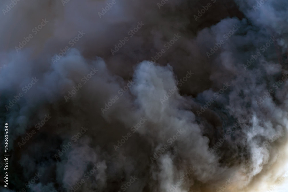 Thick black acrid smoke on the sky background