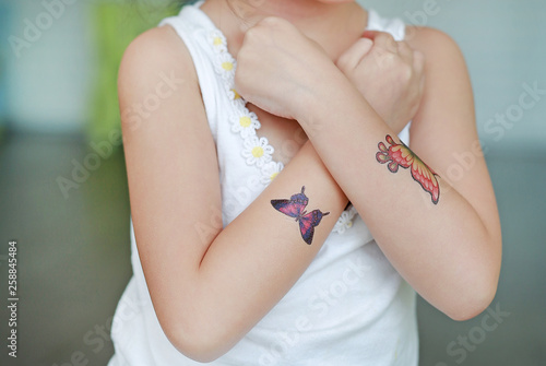 Close-up little child girl with butterfly tattoo sticker on hand, Dress up tattoos. © zilvergolf
