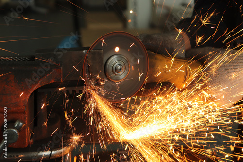 worker, grinder cuts metal and from this a huge amount of sparks