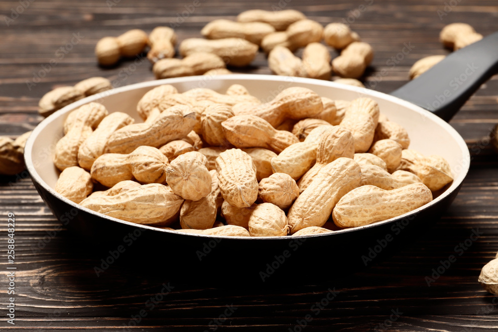 Roasted peanuts in a pan on a wooden background. Place for text. Roasted peanuts in a pan on a wooden background. Place for text.
