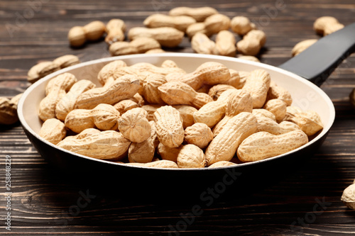 Roasted peanuts in a pan on a wooden background. Place for text.