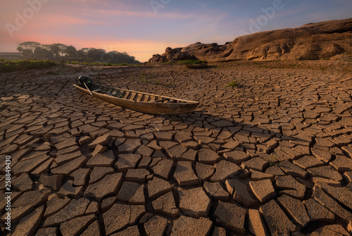Wooden boat on drought land with sunset