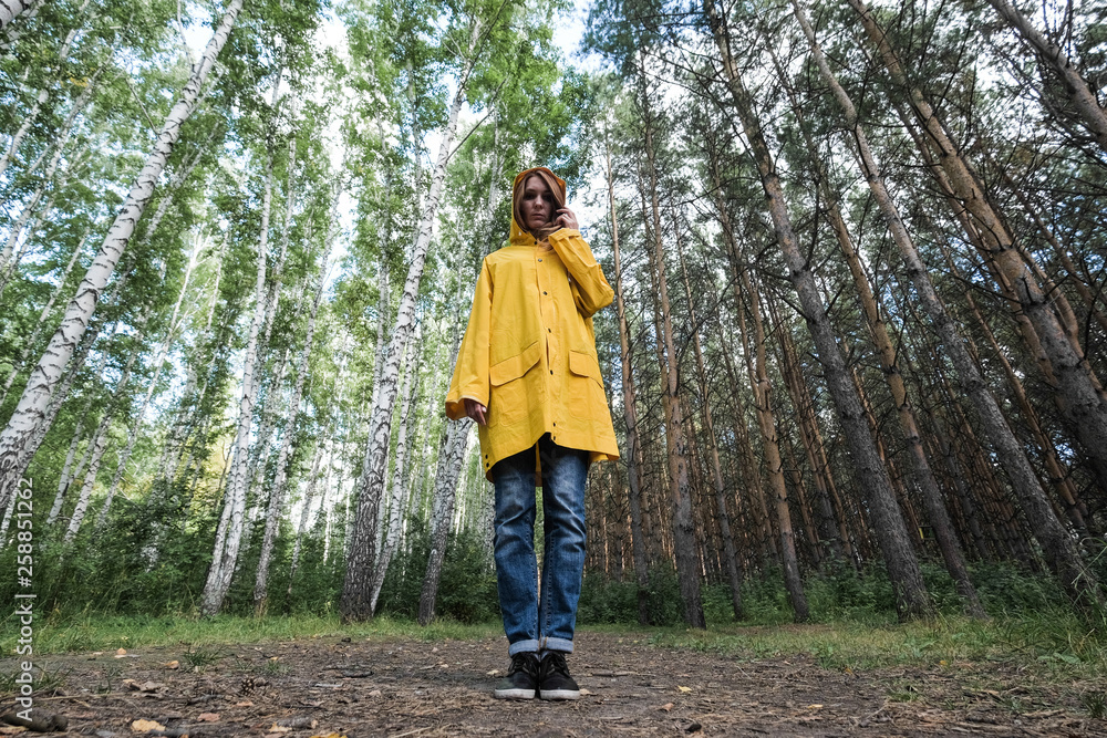 Obraz premium A woman in a yellow raincoat in the woods.