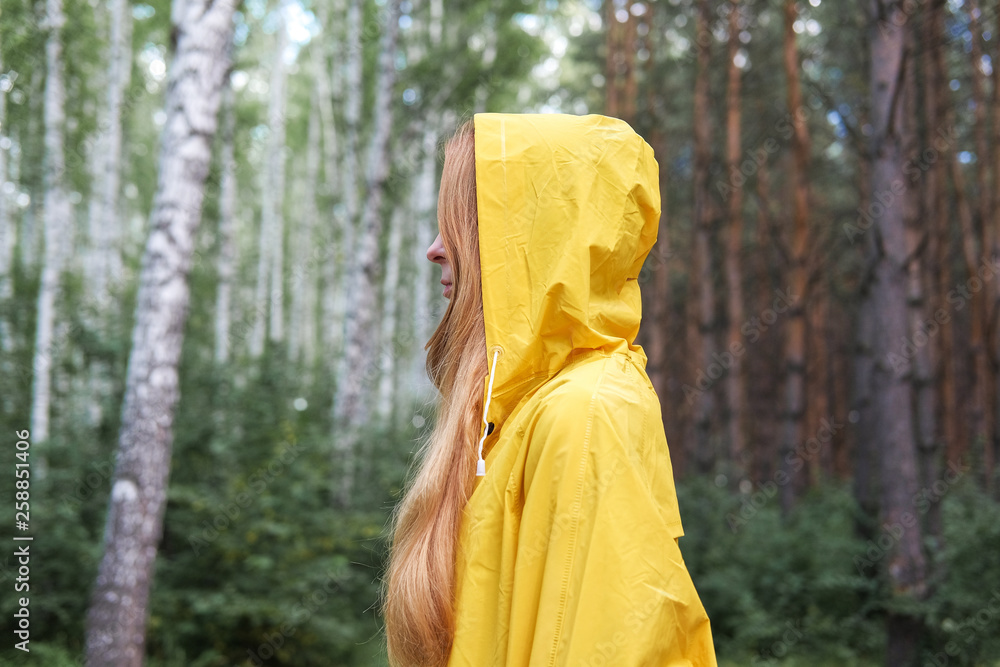 A woman in a yellow raincoat in the woods. A woman in a yellow raincoat in the woods.