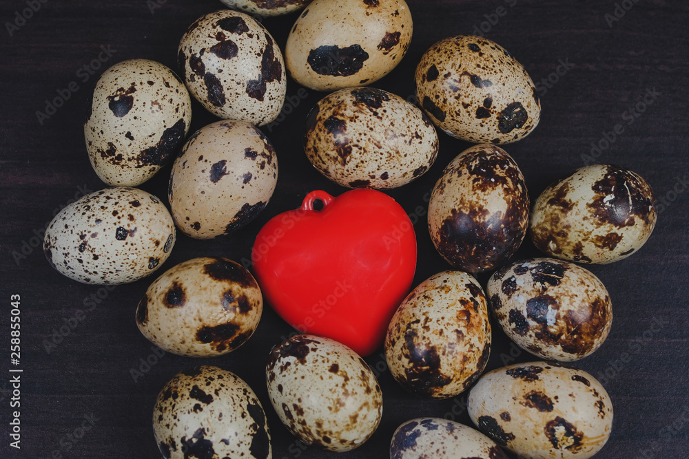 Fresh Quail eggs with red heart on background.Food and health concept. Fresh Quail eggs with red heart on background.Food and health concept.