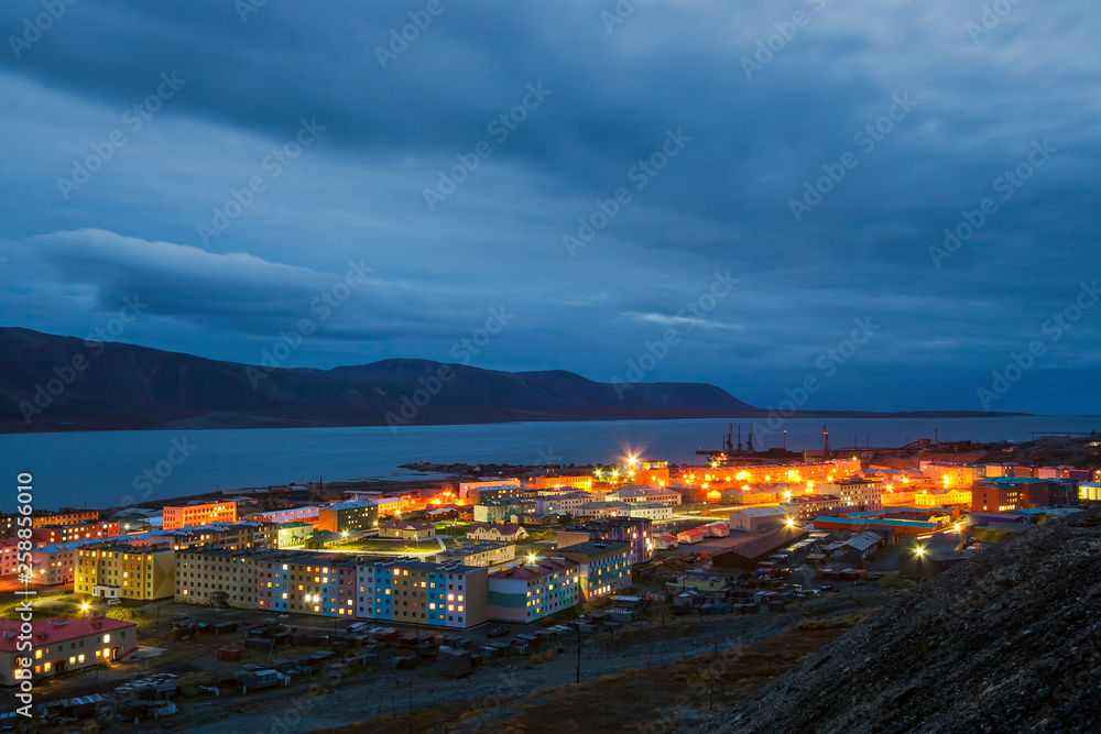Evening landscape with a small seaside town in the Arctic in Chukotka. Urban-type settlement Egvekinot. View of Kresta Bay and the mountains. Night panorama. Egvekinot, Chukotka, Far East Russia.