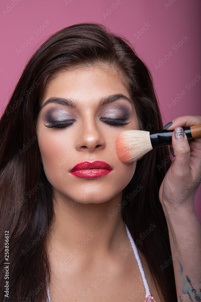 Makeup artist doing makeup for beautiful and young girl