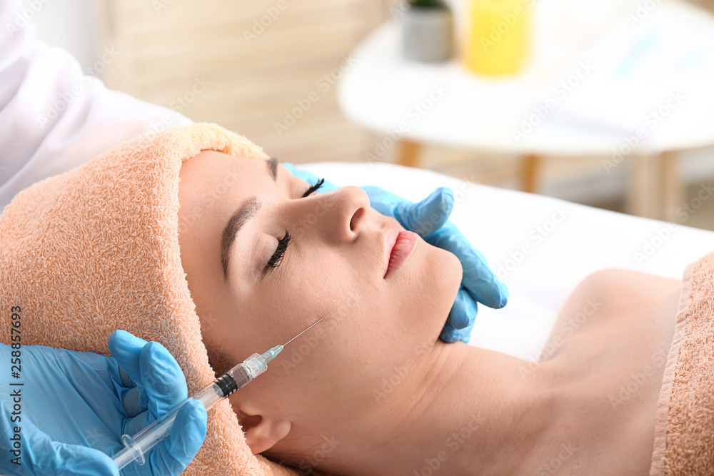 Young woman receiving filler injection in beauty salon Young woman receiving filler injection in beauty salon