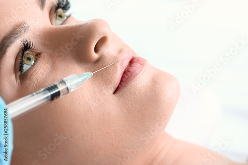 Young woman receiving filler injection in beauty salon  closeup
