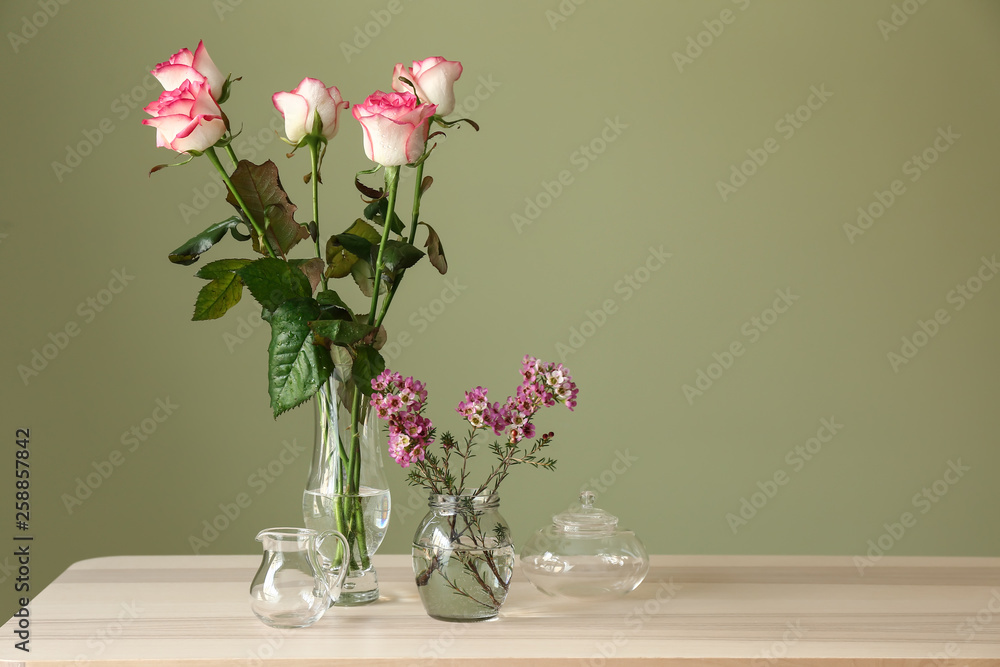 Obraz premium Beautiful flowers on table against color background