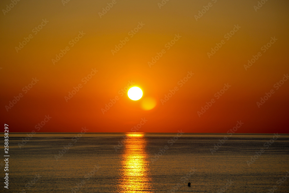 Orange sunrise on a calm and cloud free day by the mediterranean sea