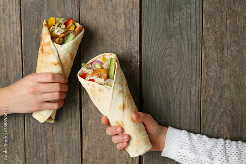 Female hands with tasty doner kebab on wooden background photo