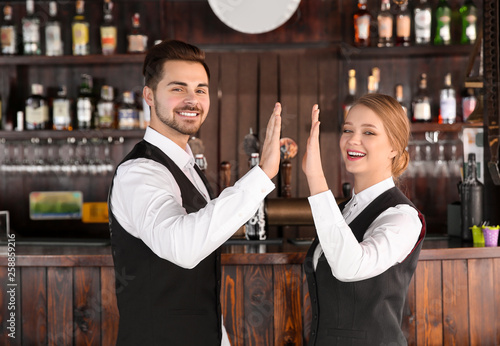 Young waiters giving each o...