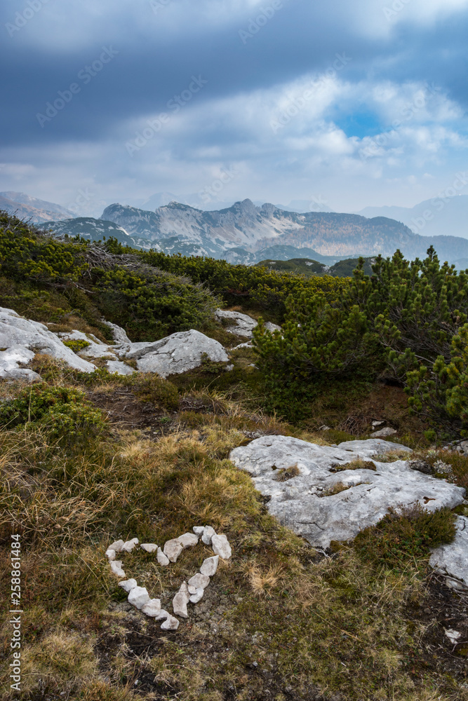 Landscape with symbol of love - heart. Landscape rocky mountains Styrian Alps in Austria. Some peaks of rocky hills with occasionally vegetation or sun shine.