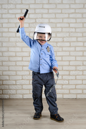 boy 4 years old plays a policeman with a baton and handcuffs