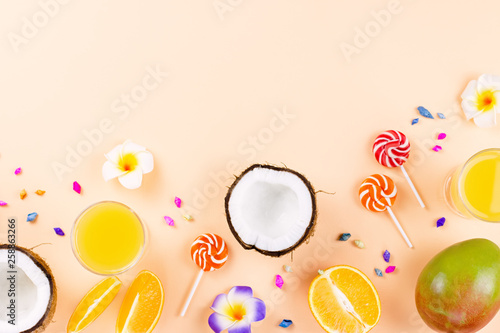 Colorful summer concept flat lay with fresh juice, tropical fruits, lollipops and multicolor seashells, copyspace