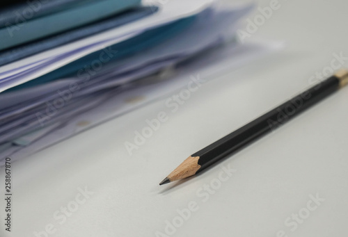 selective focus sharp pencil with business documents pile on office desk