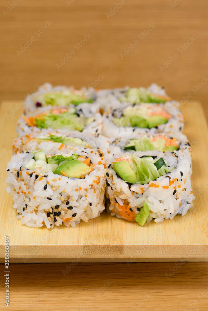sushi roll with zucchini, crab meat, salad, avocado and carrots, covered with caviar, black and white sesame sushi roll with zucchini, crab meat, salad, avocado and carrots, covered with caviar, black and white sesame