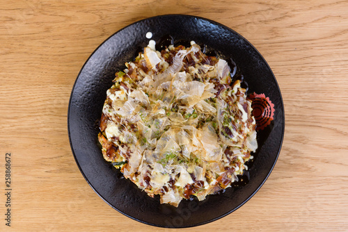 Japanese omelette Okonomiyaki, with eggs, Savoy cabbage, mayonnaise, carrot, zucchini, ginger, dried seaweed and Katsuobushi, okaka, flakes of dried meat from skipjack tuna