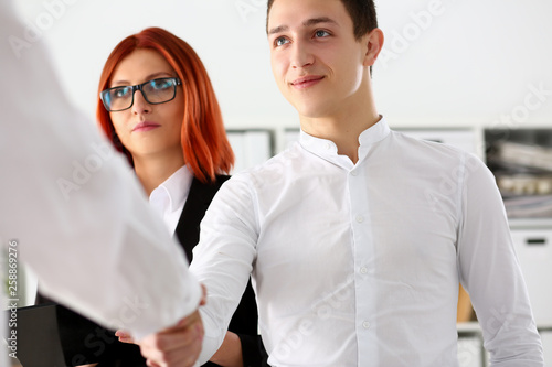 Smiling man in suit shake hands as hello in office