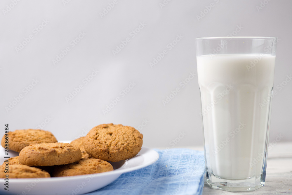 Glass of milk and cookies on a wooden white table Glass of milk and cookies on a wooden white table