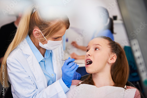 Female orthodontist examining child s teeth