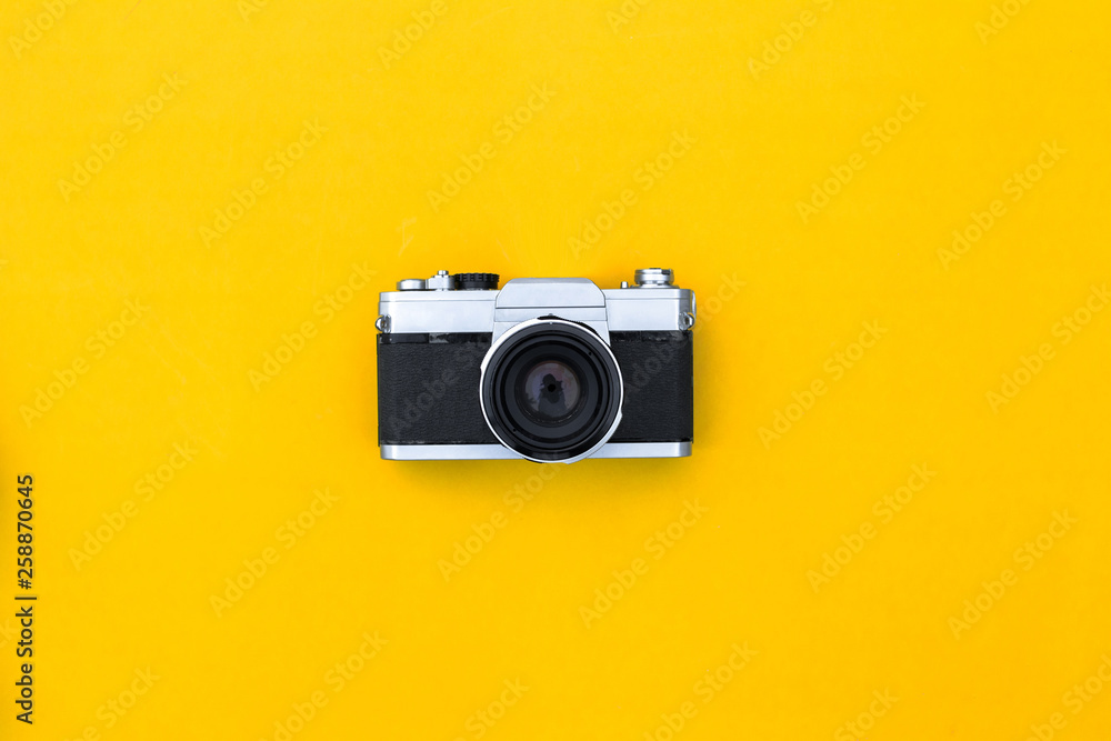 Flat lay black vintage camera and film on yellow paper background