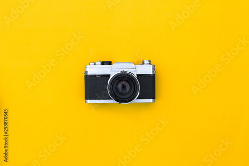 Flat lay black vintage camera and film on yellow paper background
