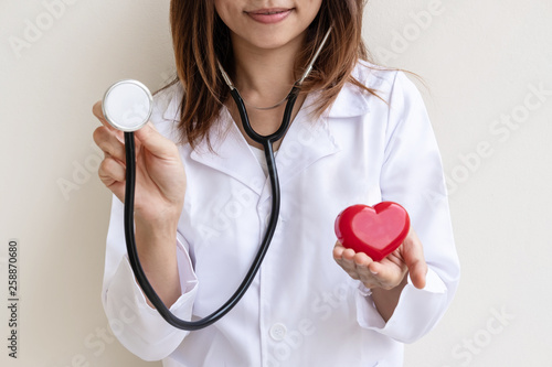 Young female doctor with the stethoscope holding red heart, cardiolog healthy care concept photo