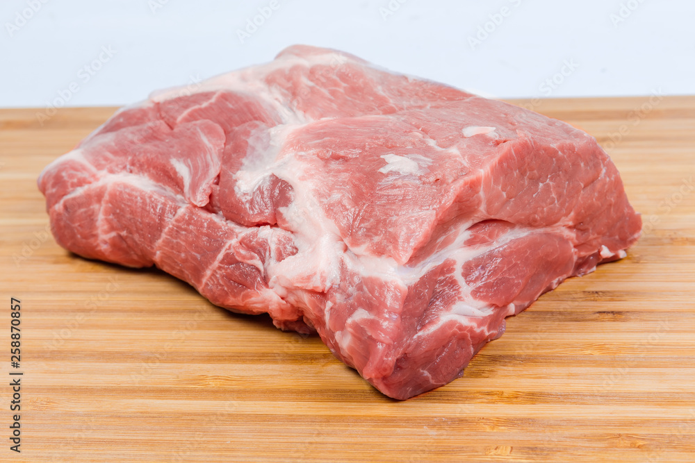 Uncooked pork neck on the wooden cutting board close-up Uncooked pork neck on the wooden cutting board close-up