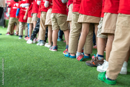 Queue of Asian kids in school uniform standing in line