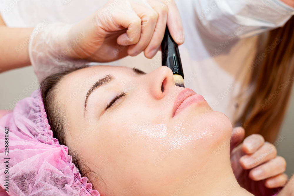 Fototapeta premium Depilation with hot wax mustache in the beauty salon. Young woman receiving facial epilation close up. Cosmetologist removes hair on face. Beauty salon, mustache depilation.