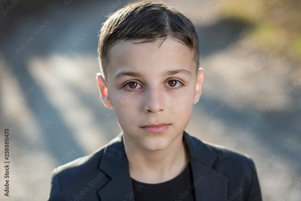 Cute little boy in elegant suit posing in front of natural background. Portrait of fashionable male child.Boy posing, natural warm color on background. Concept of children style and fashion Cute little boy in elegant suit posing in front of natural background. Portrait of fashionable male child.Boy posing, natural warm color on background. Concept of children style and fashion