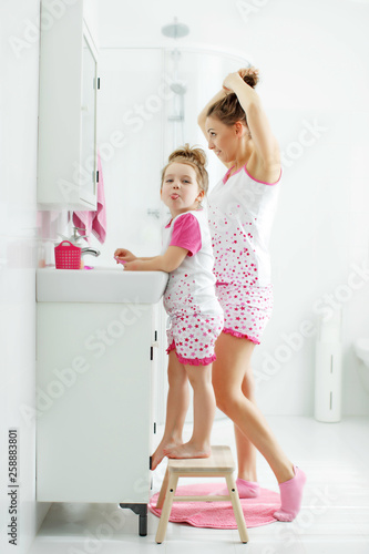 Woman and child brush their teeth 