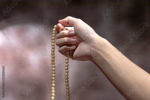 Muslim hands praying with prayer beads