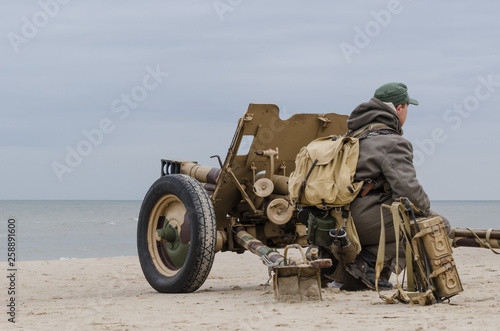 CANNON AND SOLDIER - German soldier and military equipment from the Second World War on the sea beach