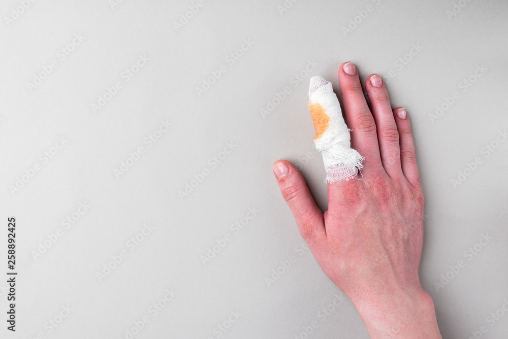 Injured painful finger with white gauze bandage on gray background. Injured painful finger with white gauze bandage on gray background.