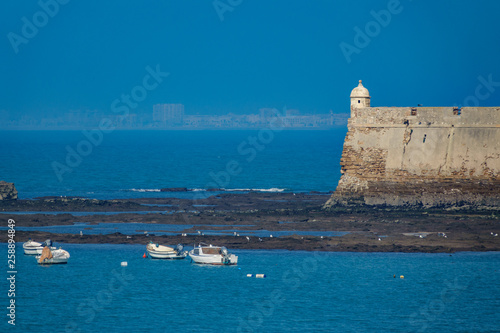 Cadiz fort near ocean in a misty day with blurred city