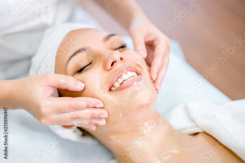 Close up of cosmetologist hands doing face massage with mask. Smiling girl on spa procedure.